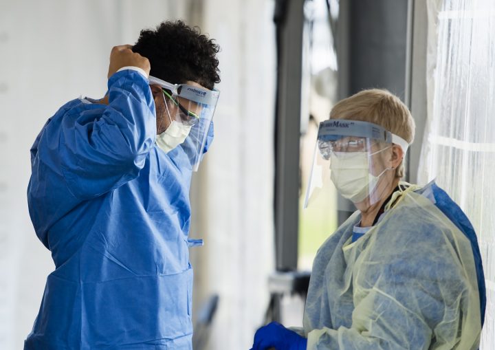 Health-care workers put on personal protective equipment before testing at a drive-thru COVID-19 assessment centre at the Etobicoke General Hospital in Toronto on Tuesday, April 7, 2020.