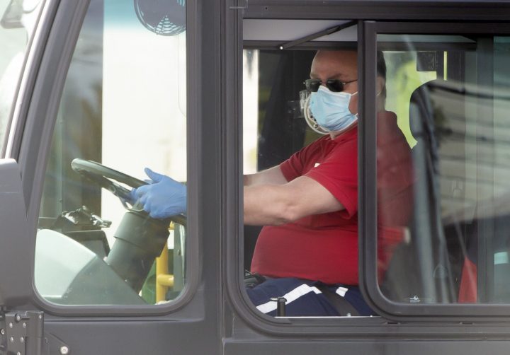 A Toronto Transit Commission bus driver wears a mask and gloves as he drives a bus in Toronto on Tuesday, April 14, 2020.