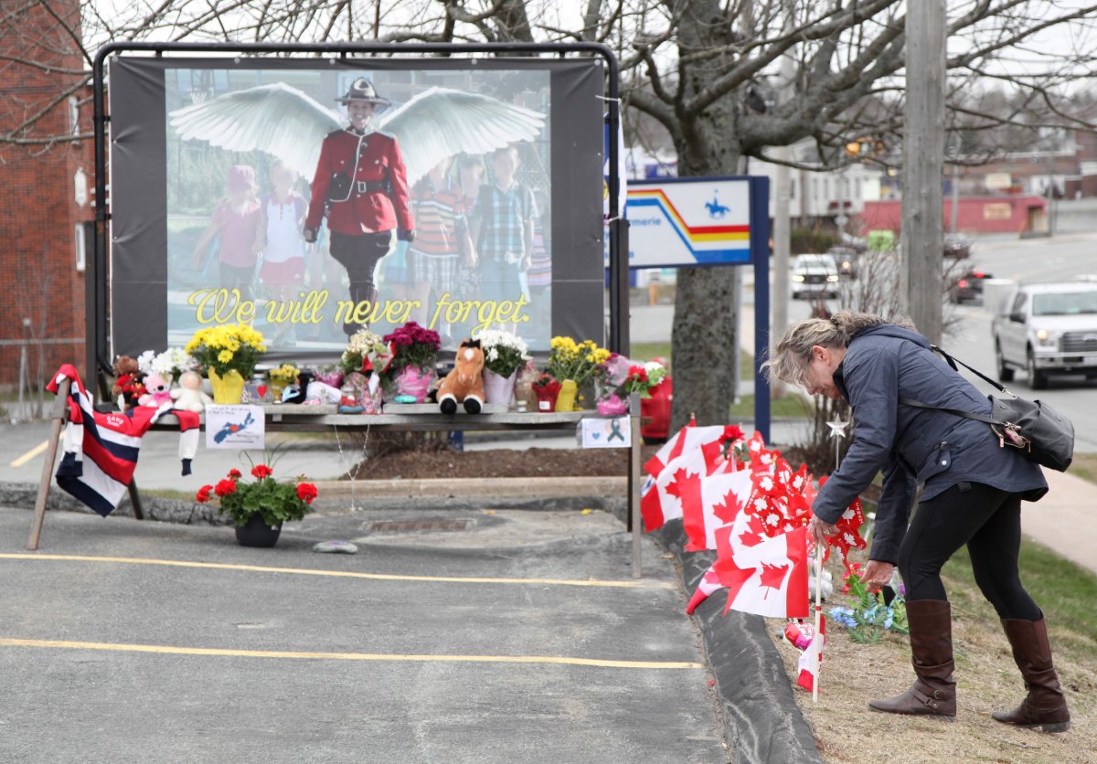 A woman places a pinwheel in front of a mural dedicated to slain RCMP Const. Heidi Stevenson, prior to a province-wide, two minutes of silence for the 22 victims of last weekend's shooting rampage, held in front of the RCMP detachment in Cole Harbour, N.S., Friday, April 24, 2020.