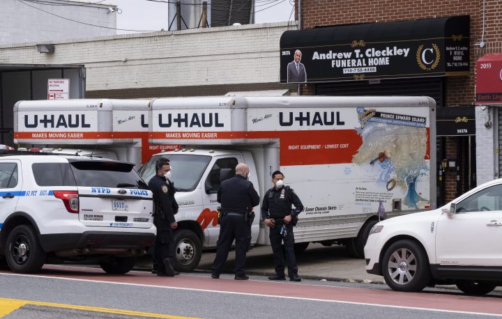 New York City police officers stand by at the Andrew T. Cleckley Funeral Home in the Brooklyn borough of New York, Wednesday, April 29, 2020. Police responded to a report of human bodies in vehicles, which they determined were connected to the nearby funeral home. The New York Police Department notified the state Department of Health, which oversees funeral homes. The coronavirus pandemic has overrun most funeral homes and morgues in New York City.