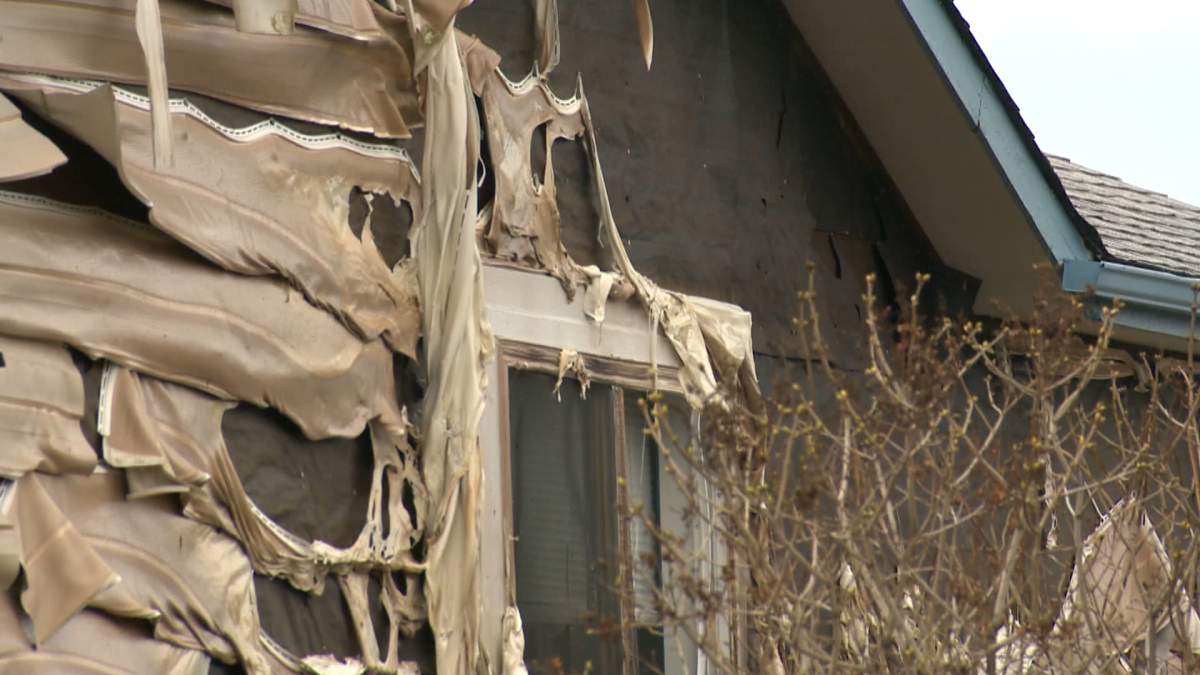 Melted siding seen on the side of a home next door to a house that was extensively damaged by fire in Abbeydale.