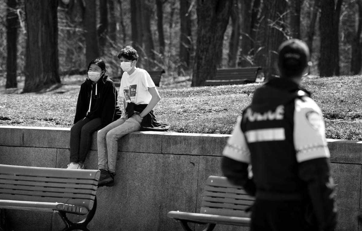 A Montreal police officer looks at a pair of visitors at Mont Royal Park, Saturday April 4, 2020. Phil Carpenter/Global News