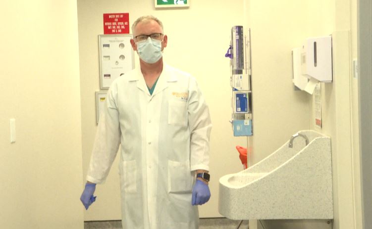 Dr. Chris Lee wears preps for a patient by putting on personal protective equipment.