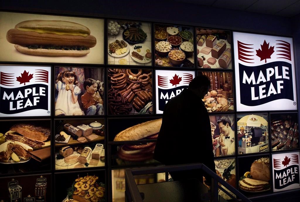 A Maple Leaf Foods employee walks past a Maple Leaf sign at the company's meat facility in Toronto on Monday, Dec. 15, 2008.