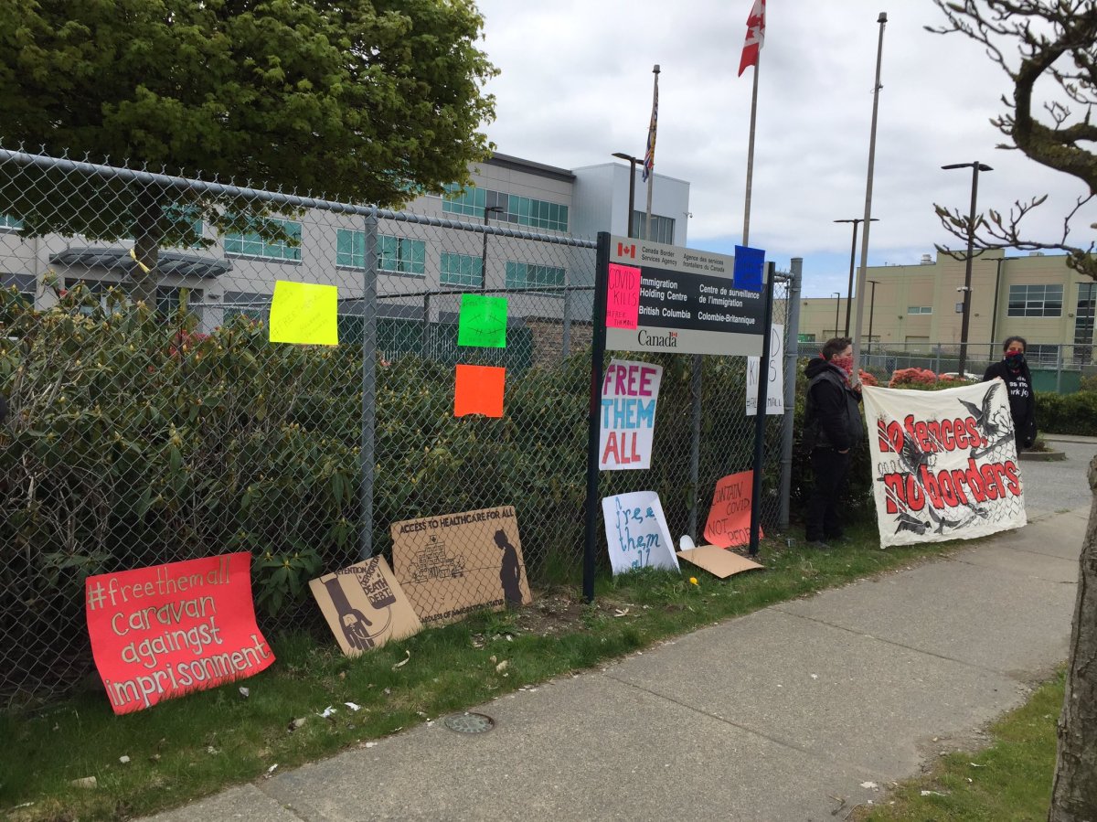 Protesters stand near signs posted at the Surrey Immigration Holding Centre calling for the release of detained migrants during the COVID-19 pandemic on April 19, 2020.