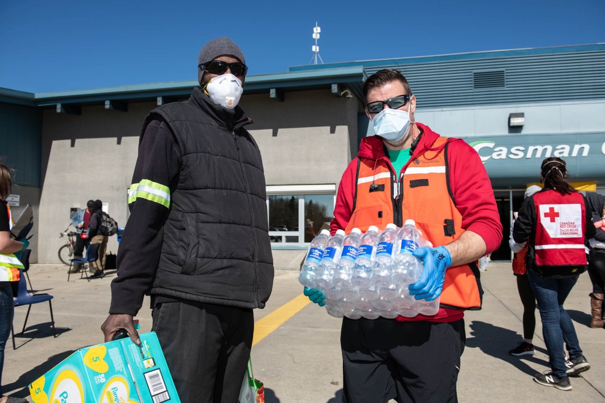 A Red Cross volunteer supplies water and diapers to flood evacuee Abdigani Abokar (left) at an evacuee registration centre at an ice arena in the Thickwood Heights neighbourhood of Fort McMurray, Alta. on Tuesday, April 28, 2020. A boil water advisory in Fort McMurray could be lifted sooner than originally anticipated.