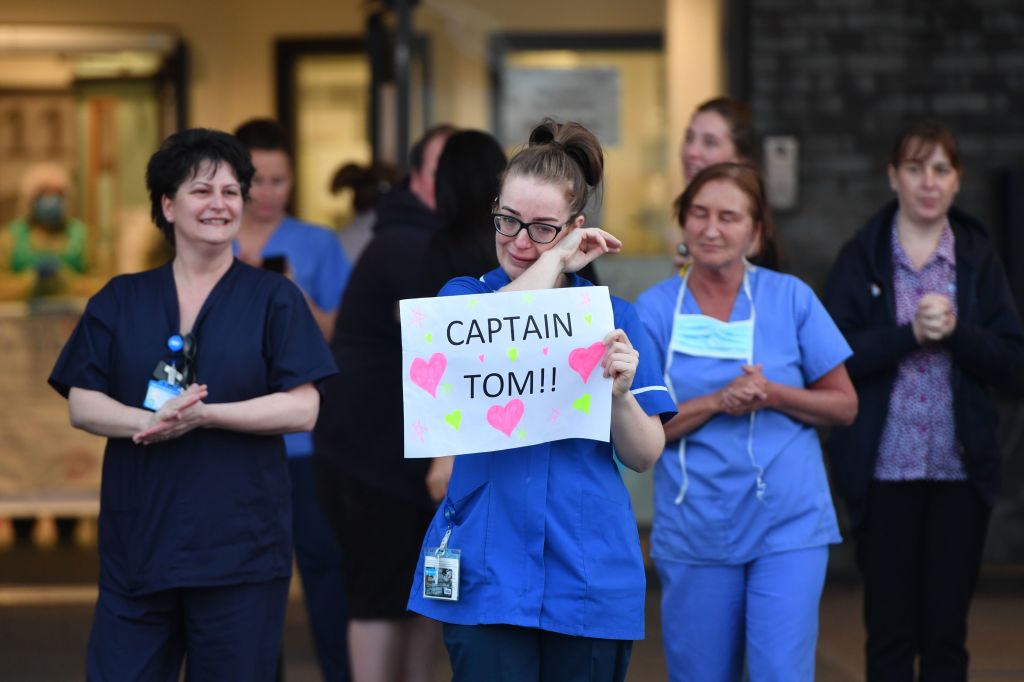 An NHS staff member wipes her eyes as she holds a sign to thank British veteran Captain Tom Moore, at Aintree University Hospital in Liverpool, north-west England on April 16, 2020.