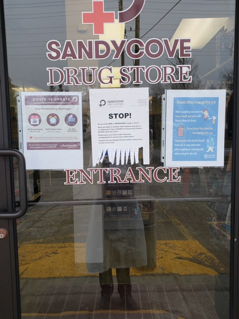 Signs outside of the Sandycove Drugstore encourage customers to not enter if they have COVID-19 symptoms. Photo by Cristina Privado