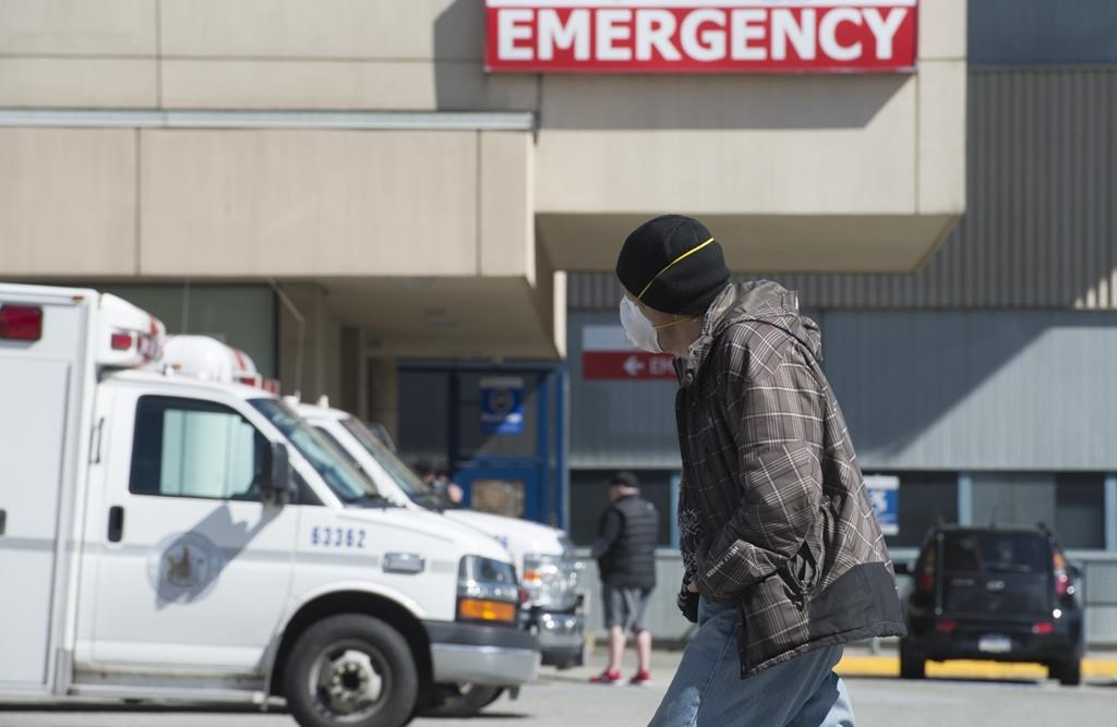 A man wears a protective face mask as he walks past the emergency department of the Royal Columbian Hospital in New Westminster, B.C. Friday, April 3, 2020. Health-care providers are warning of an unseen toll COVID-19 could take if people die because they are too afraid to go to an emergency room for serious health issues unrelated to the pandemic. THE CANADIAN PRESS/Jonathan Hayward.