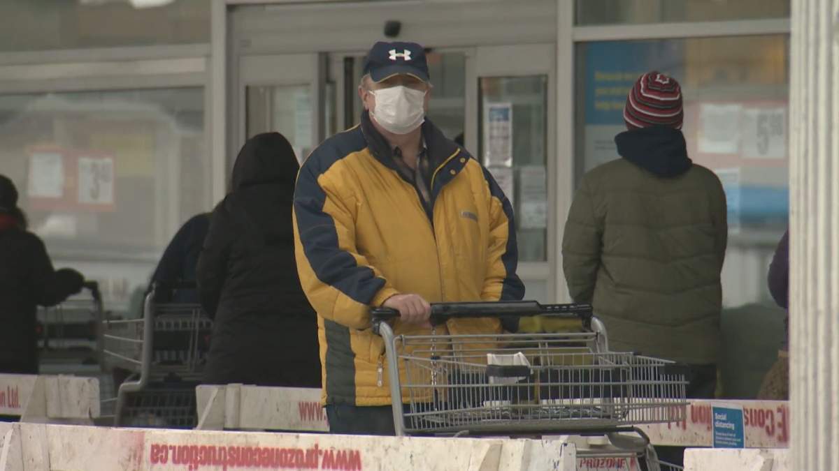 Man stands in a lineup to be let into an Edmonton grocery store amid the COVID-19 pandemic.