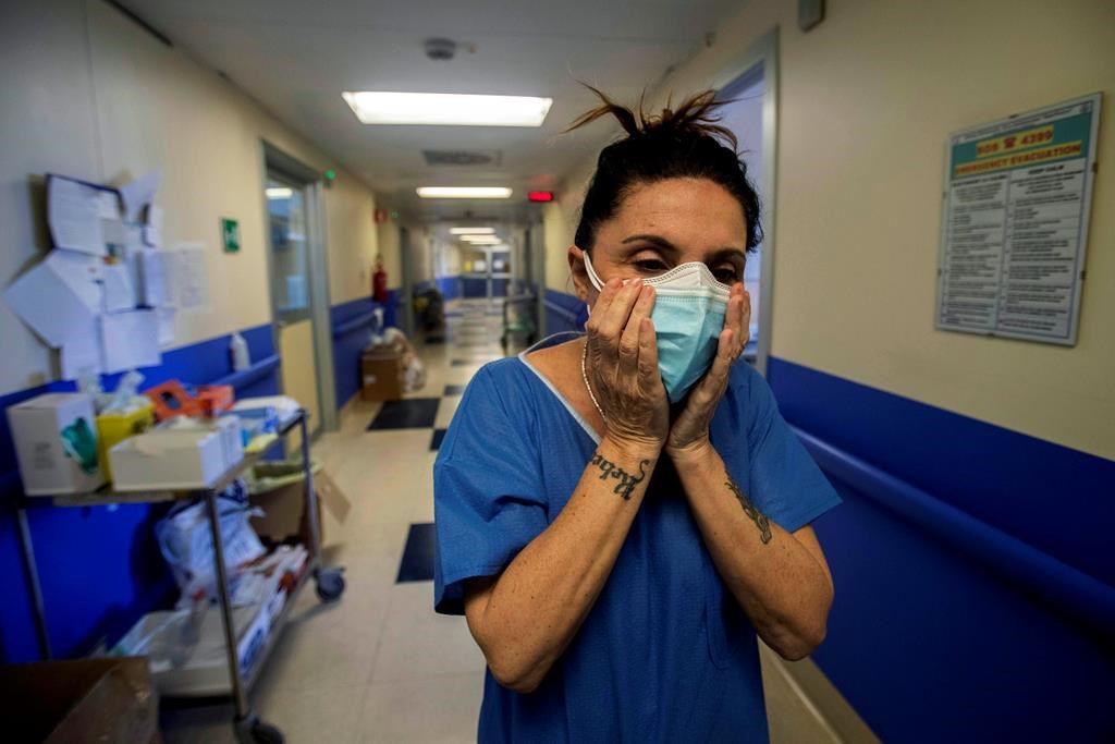Nurse Cristina Settembrese fixes two masks to her face during her work shift in the COVID-19 ward at the San Paolo hospital in Milan, Italy, April 10, 2020.
