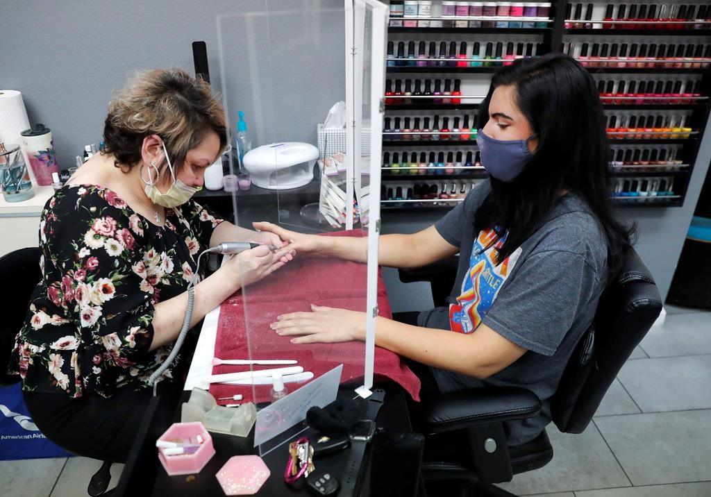 FILE - In this April 24, 2020, file photo, manicurist Rhonda Simpson, left, polishes nails for her customer Faith at the reopened Salon A la Mode in Dallas.