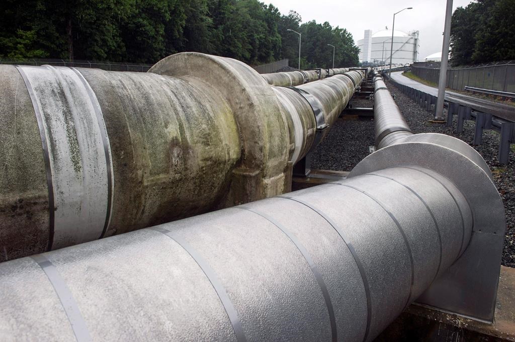 In this June 12, 2014, photo, pipes carrying liquified natural gas to and from a holding tank, seen in background, at Dominion Energy's Cove Point LNG Terminal in Lusby, Md. THE CANADIAN PRESS/AP/Cliff Owen.