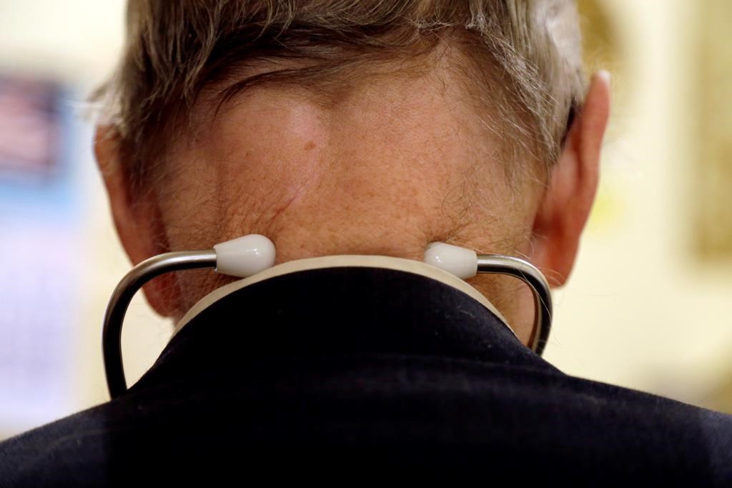 In this Tuesday, Oct. 30, 2012 photo, a doctor wears a stethoscope around his neck as he tends to patients in his office in Illinois.