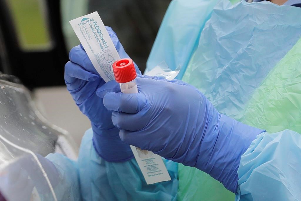 FILE - In this April 2, 2020, file photo a nurse holds a vial and a swab at a coronavirus testing station.