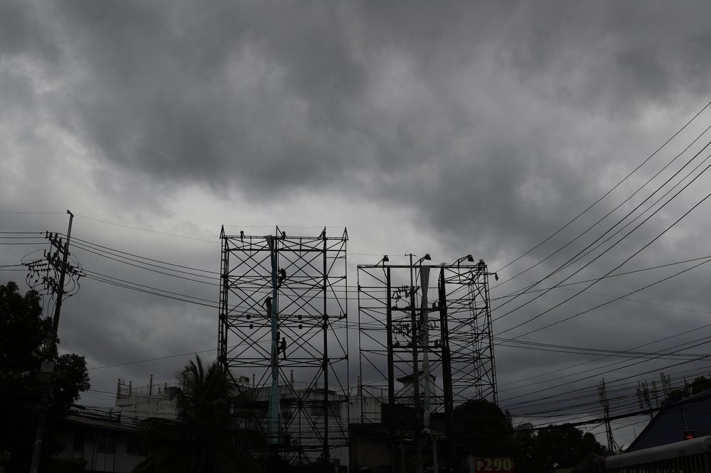 Dark clouds envelop the skies as workers fold a billboard to prepare for the coming of typhoon Vongfong in Manila, Philippines Thursday May, 14, 2020. The first typhoon to hit the country this year roared toward the eastern Philippines on Thursday as authorities work to evacuate tens of thousands of people while avoiding overcrowding in shelters that could spread the coronavirus. 
