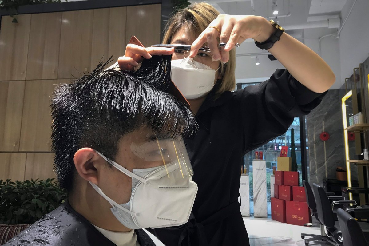 File photo of a barber wearing a mask while cutting a client's hair. 