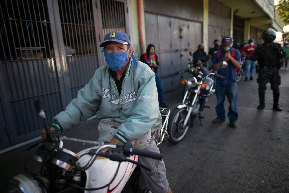 A man waits in line to fill up his motorcycle with gasoline outside one of the few open fuel stations during a lockdown to contain the spread of the new coronavirus in Caracas, Venezuela, Friday, March 27, 2020. 