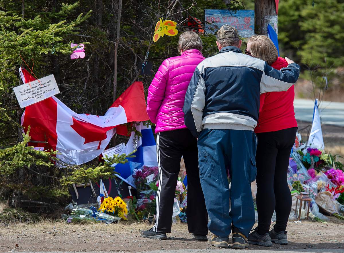 A family pays their respects to victims of the mass killings at a checkpoint on Portapique Road in Portapique, N.S. on Friday, April 24, 2020.