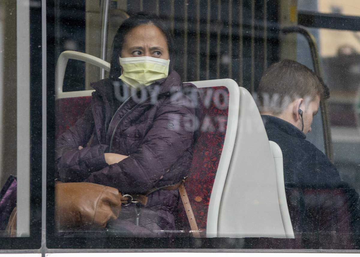 A woman wears a mask as she rides a TTC streetcar in Toronto on Friday, March 20, 2020.