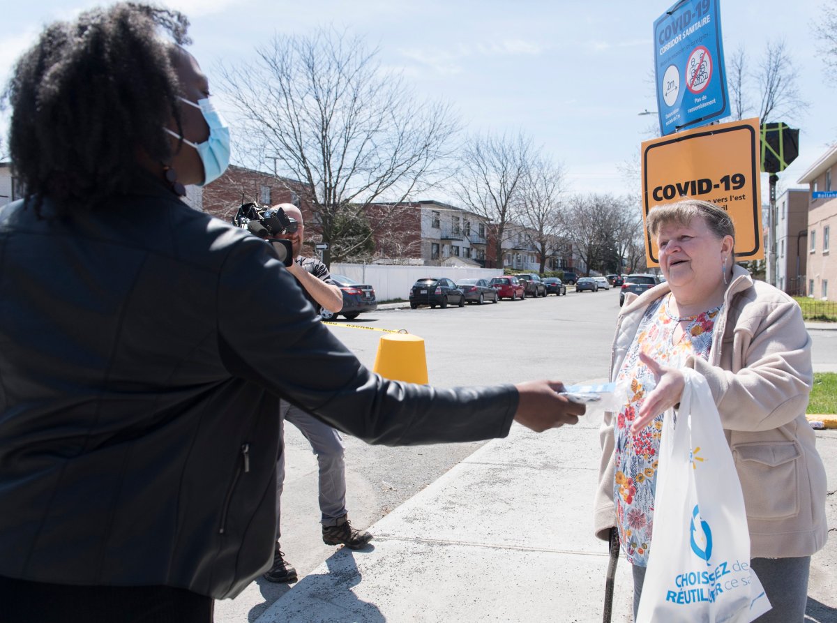 A volunteer, left, hands out a COVID-19 kit which includes, masks, gloves and information in Montreal North, Saturday, May 2, 2020, as the COVID-19 pandemic continues in Canada and around the world. 