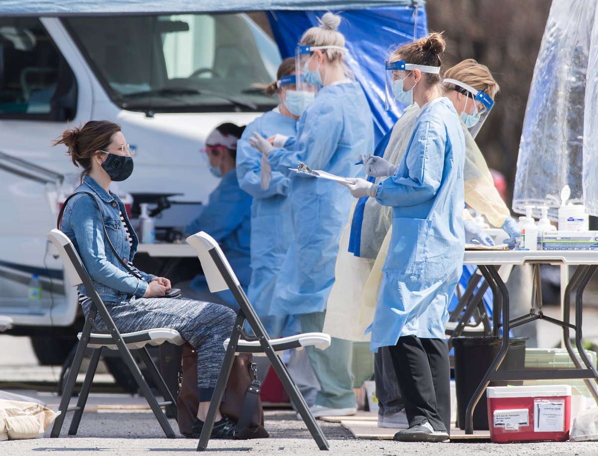 A health-care worker talks to a woman at a temporary COVID-19 test clinic in the Montreal borough of Saint-Michel, Sunday, May 3, 2020, as the COVID-19 pandemic continues in Canada and around the world. 