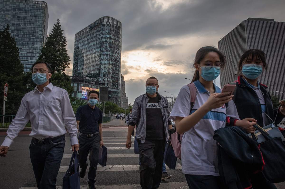 People wearing protective face masks cross a road during evening rush-hour on the first day of China's National People's Congress (NPC) in Beijing, China, 22 May 2020.