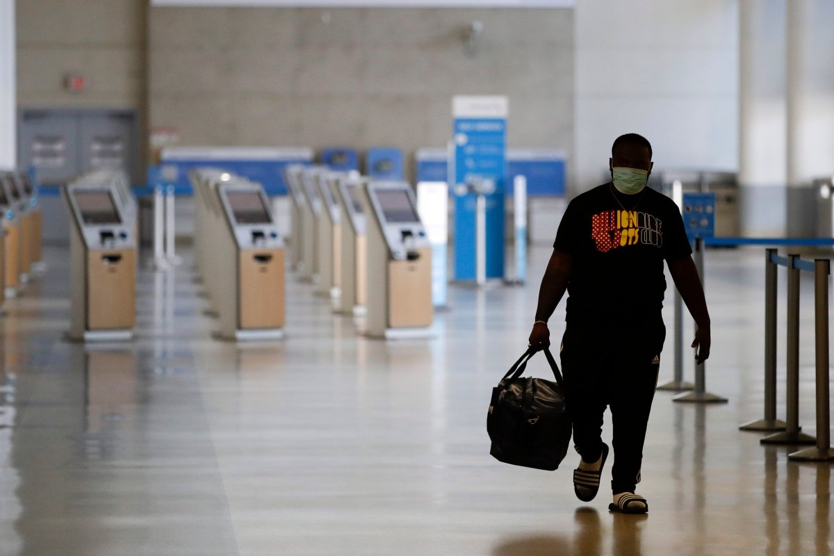 A traveler walks in a mostly empty American Airlines terminal at the Los Angeles International Airport, Thursday, May 28, 2020, in Los Angeles.