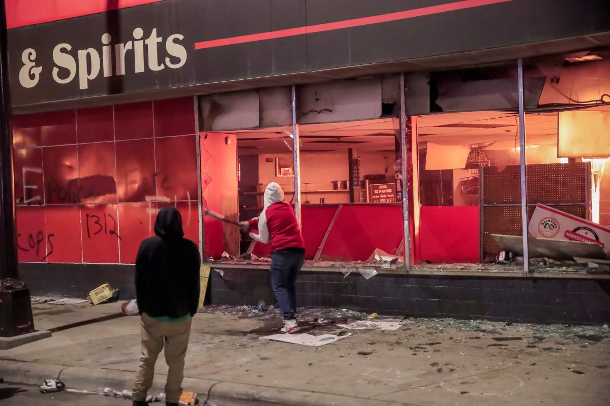 Protesters loot a burning liquor store across the street from the Minneapolis Police Department 3rd Precinct during protests over the arrest of George Floyd. EPA/TANNEN MAURY