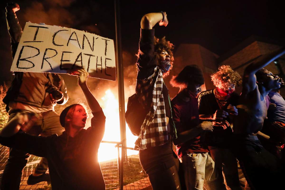 Protestors demonstrate outside of a burning Minneapolis 3rd Police Precinct, Thursday, May 28, 2020, in Minneapolis. (AP Photo/John Minchillo)
