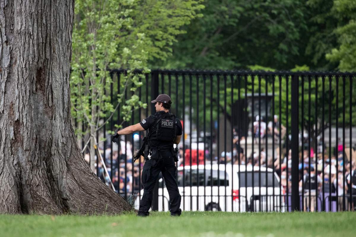 A U.S. Secret Service officer stands inside the fence at the White House as demonstrators protest the death of George Floyd, a black man who died in police custody in Minneapolis, Friday, May 29, 2020, in Washington. (AP Photo/Alex Brandon)