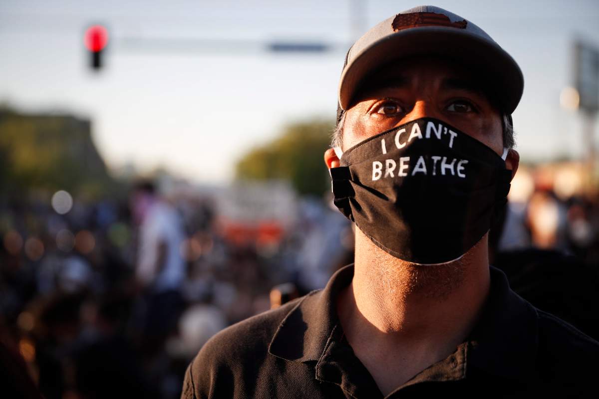 A man attends a protest outside the Minneapolis 5th Police Precinct while wearing a protective mask that reads "I CAN'T BREATHE", Saturday, May 30, 2020, in Minneapolis.