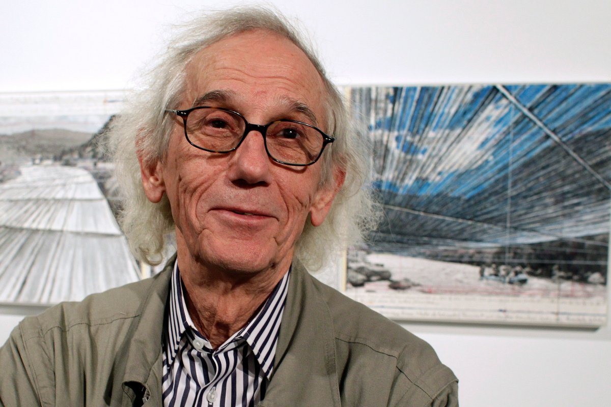 This Jan. 23, 2013 file photo shows artist Christo posing in front of his proposed "Over the River" project at the Metropolitan State University Center for Visual Art in Denver. Christo, known for massive, ephemeral public arts projects, has died. His death was announced Sunday, May 31, 2020, on Twitter and the artist's web page. He was 84.