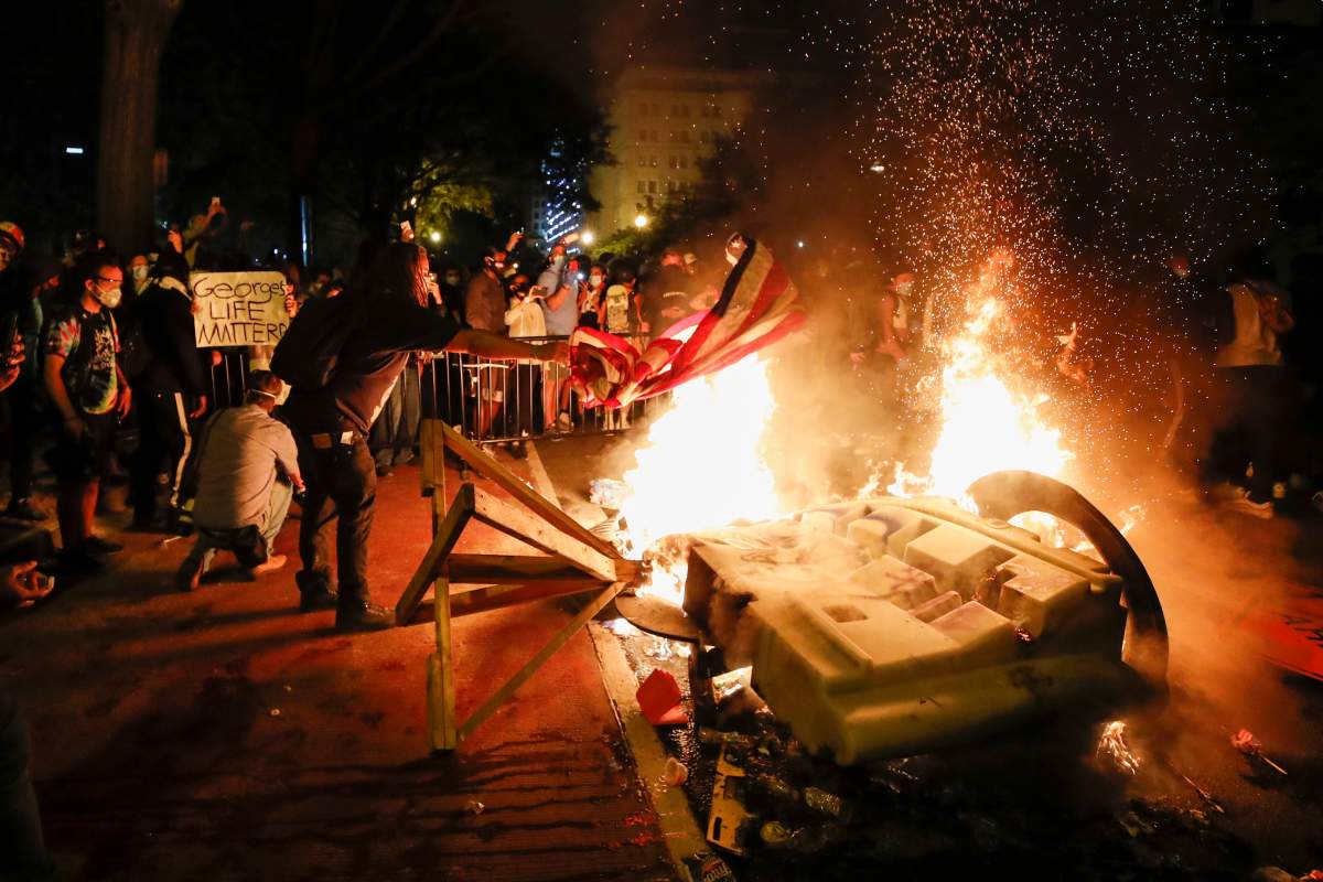 Demonstrators start a fire as they protest the death of George Floyd, Sunday, May 31, 2020, near the White House in Washington. Floyd died after being restrained by Minneapolis police officers