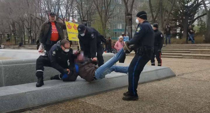A still image taken from a YouTube video showing a protester being taken away at the Alberta legislature in May 2020.