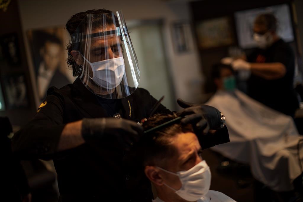 Hairdresser Enric Mas cuts the hair of a customer at his hairdressing salon in Caldas de Montbui, near Barcelona, Spain, Tuesday, May 5, 2020.