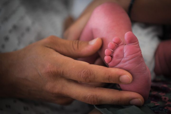 FILE: A mother holds the foot of her newborn baby on July 7, 2018.