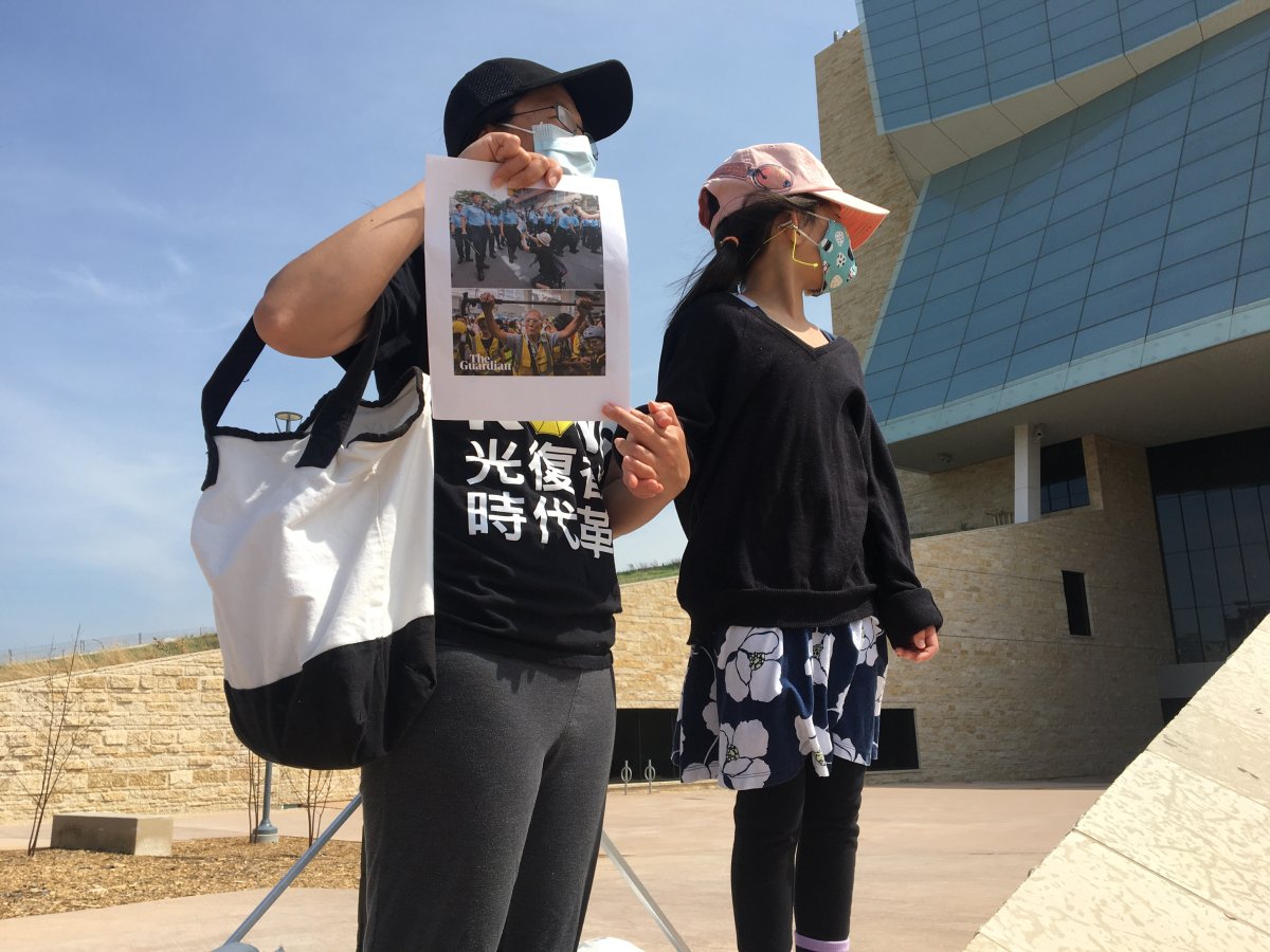 A woman holding images of recent protests in Hong Kong and a young girl, both wearing masks, joined a Winnipeg rally Saturday against a proposed security law in Hong Kong.  