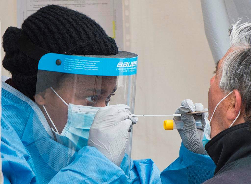 A health-care worker prepares to swab a man at a walk-in COVID-19 test clinic in Montreal North, Sunday, May 10, 2020, as the COVID-19 pandemic continues in Canada and around the world.