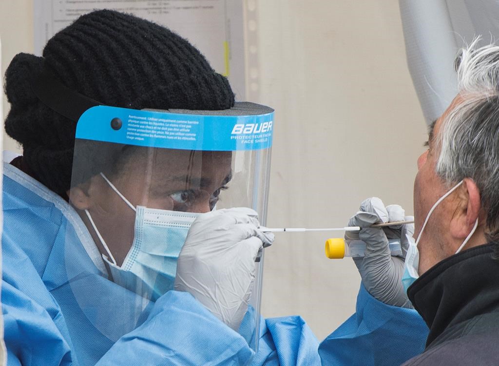 A health-care worker prepares to swab a man at a walk-in COVID-19 test clinic in Montreal North, Sunday, May 10, 2020, as the COVID-19 pandemic continues in Canada and around the world.