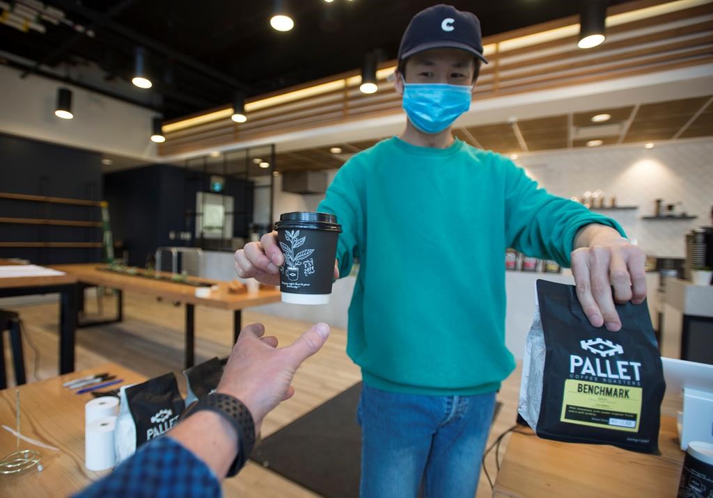 A server wears a protective face mask as he passes a coffee to a customer in Vancouver.
