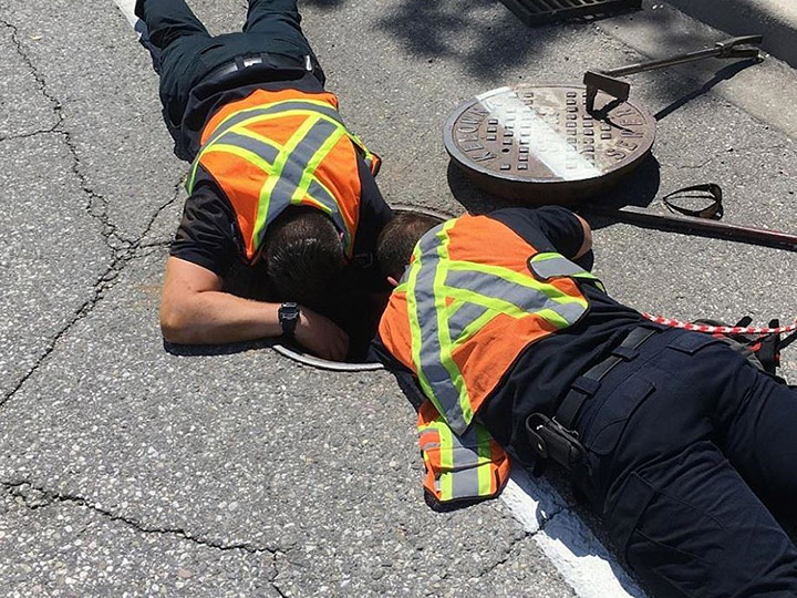 Two rescue members look down the storm drain on Sunday.
