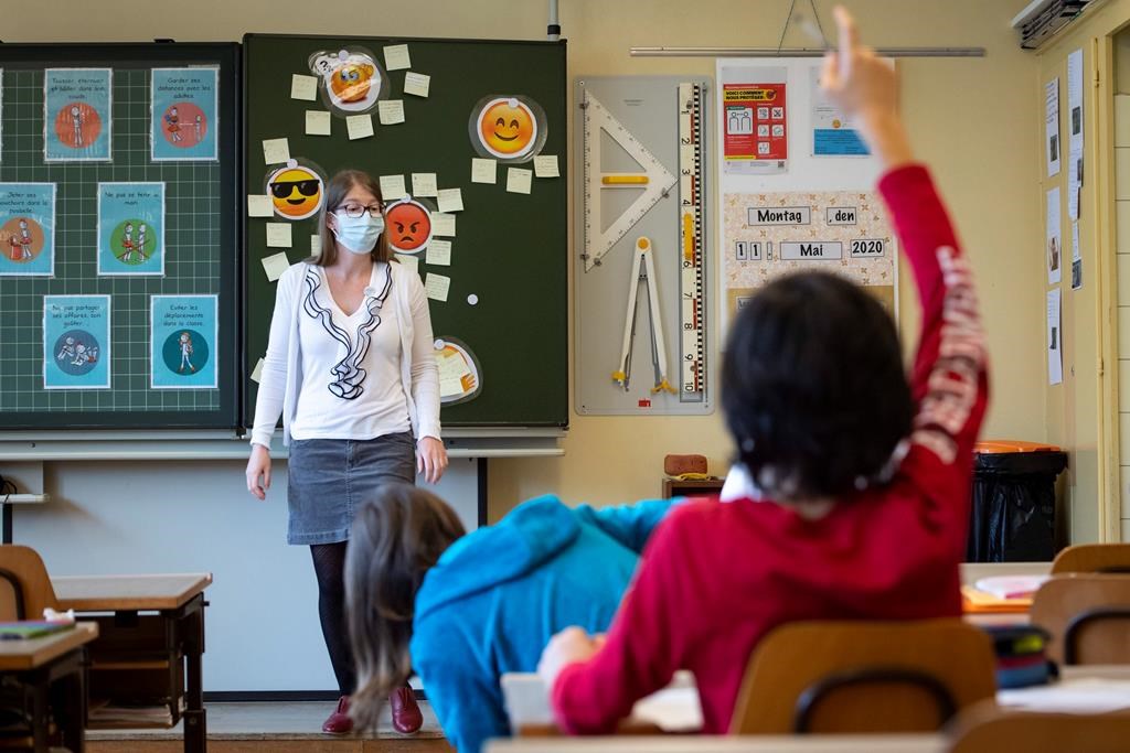 A teacher wearing protective face mask as she teaches close to pupils at a primary school.
