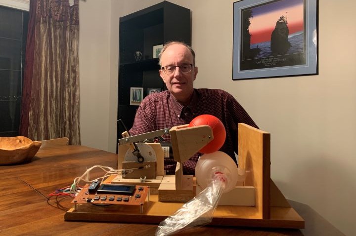 Gordon Payne sits alongside his homemade ventilator, which he created partly by using items that he found around the house.