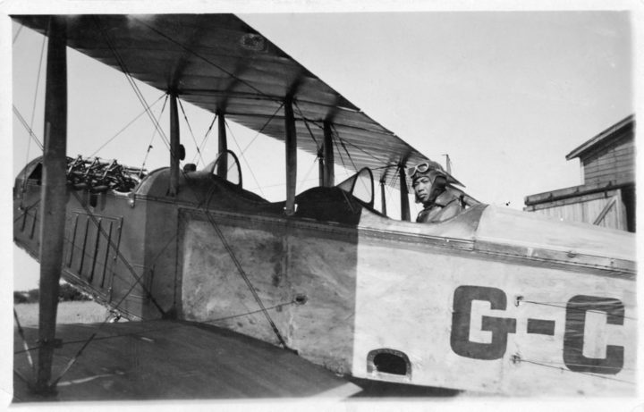 Chinese man seated in cockpit of biplane.