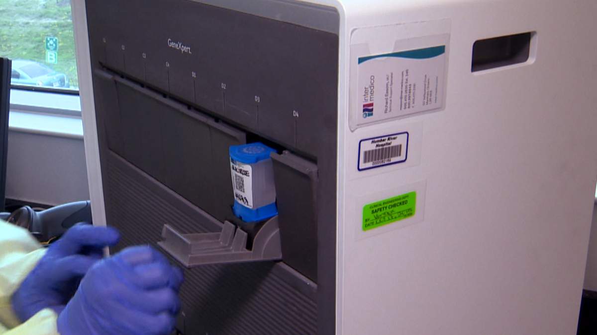 Placing a cartridge with a COVID-19 test sample into an analyzer machine.