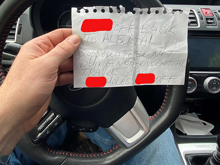 A man in Revelstoke, B.C., holds a handwritten note that was left on his vehicle last week. The man recently moved to Revelstoke, but the vehicle had Alberta licence plates.