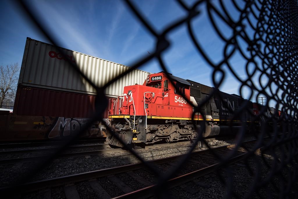 CN Rail locomotives are moved on tracks past cargo containers sitting on idle train cars at port in Vancouver, on Friday, February 21, 2020.