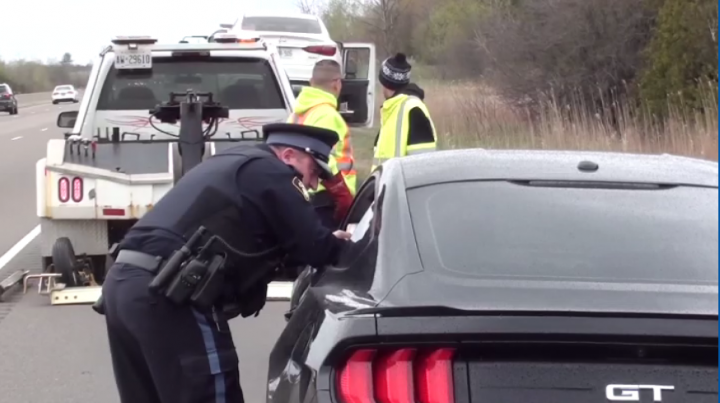 An officer speaks to a driver who was pulled over as part of speed enforcement.