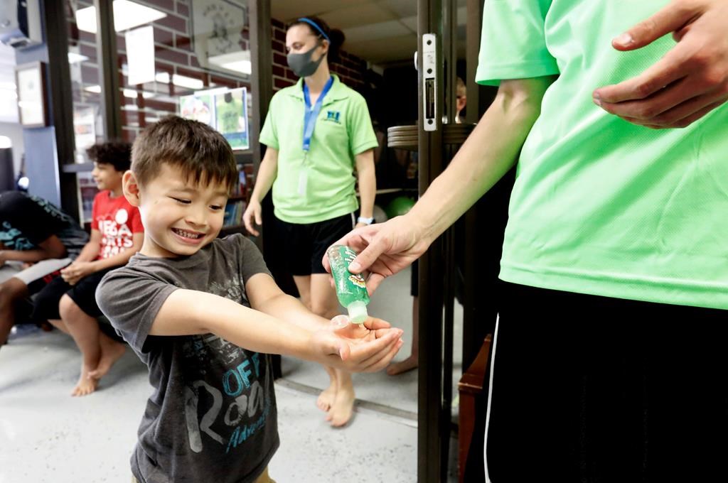 In this file photo, a child takes hand sanitizer during martial arts daycare summer camp. Pointe-Claire and Sainte-Anne-de-Bellevue have announced they will be cancelling summer camps amid the coronavirus pandemic. Wednesday, May 27, 2020.
